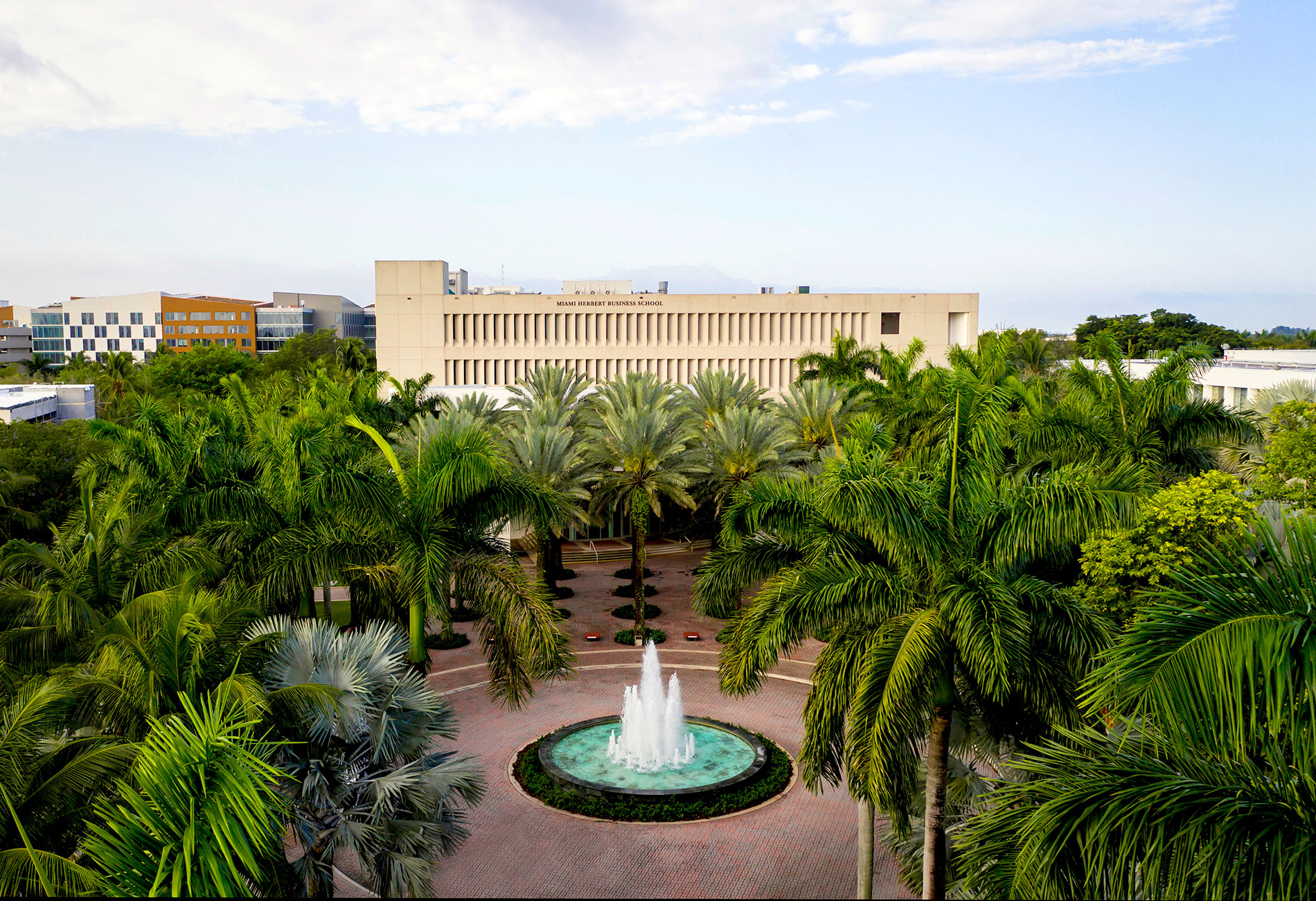 Aerial view of Miami Herbert Business school building, fountain and palm trees in the foreground. 