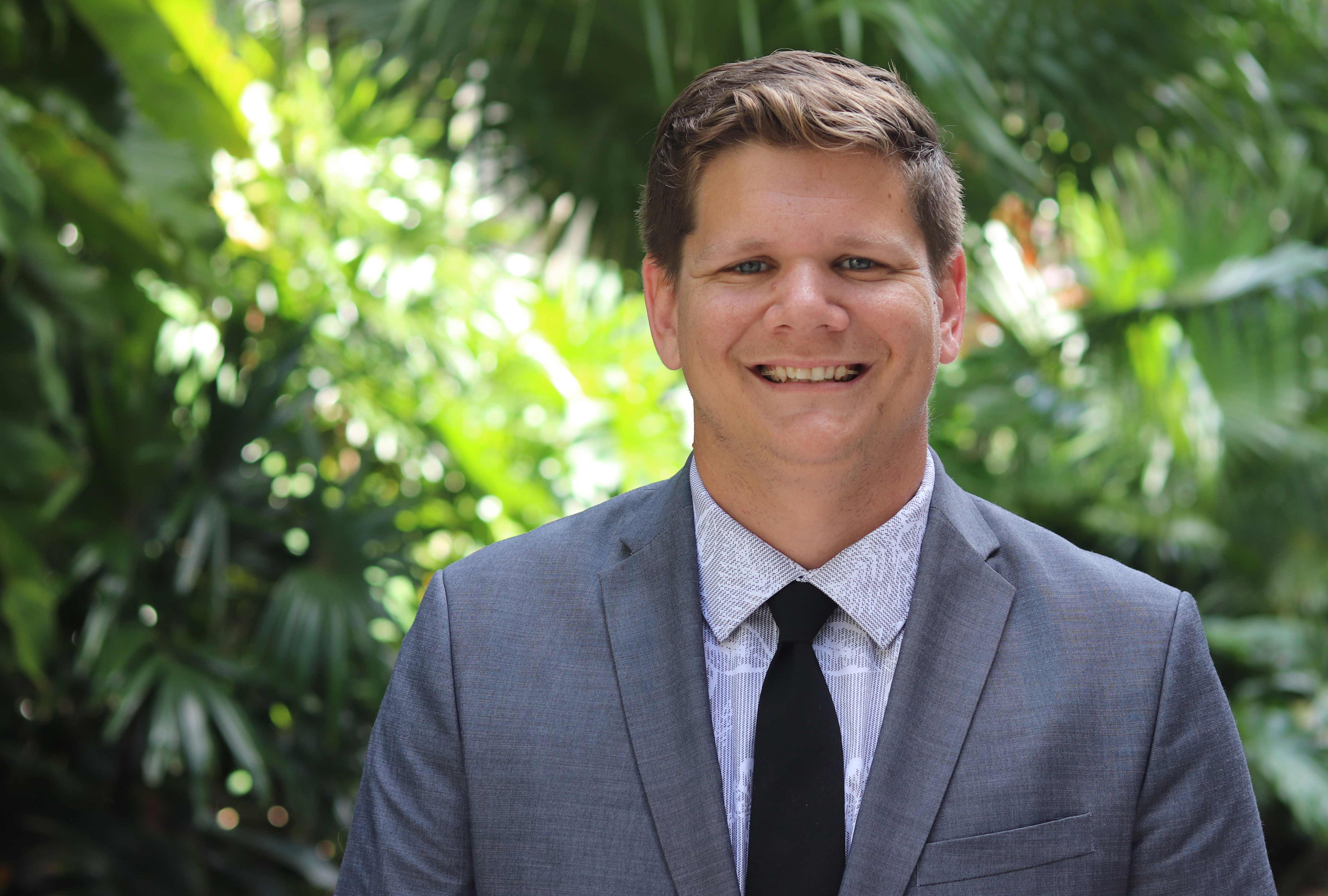 Mark Jackson poses for a headshot in front of greenery