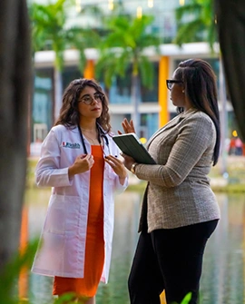 Three students sit outside on campus having a discussion