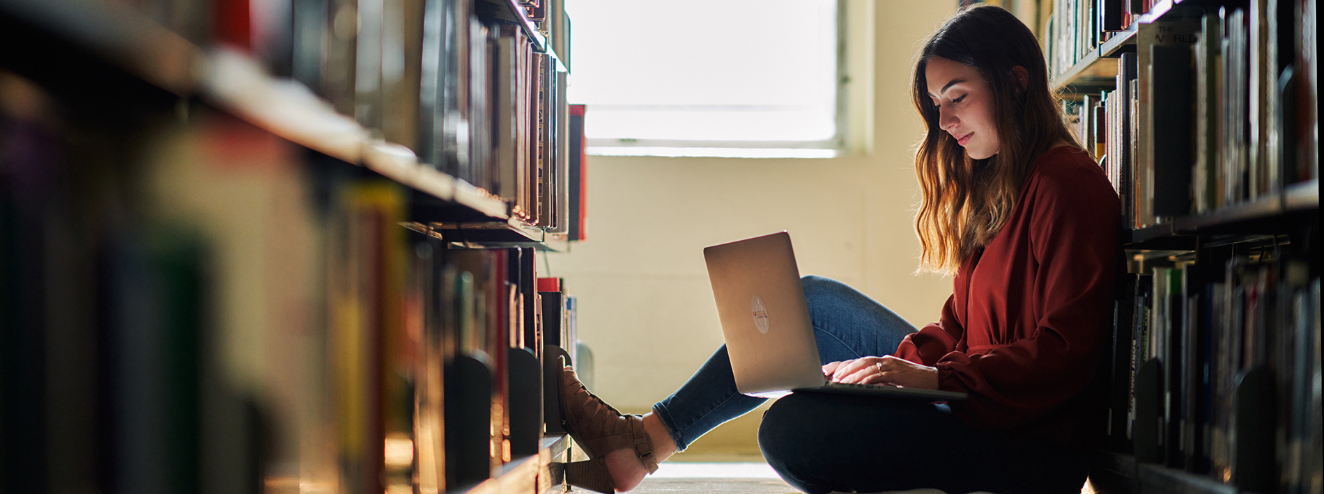 woman sitting in a library with a laptop