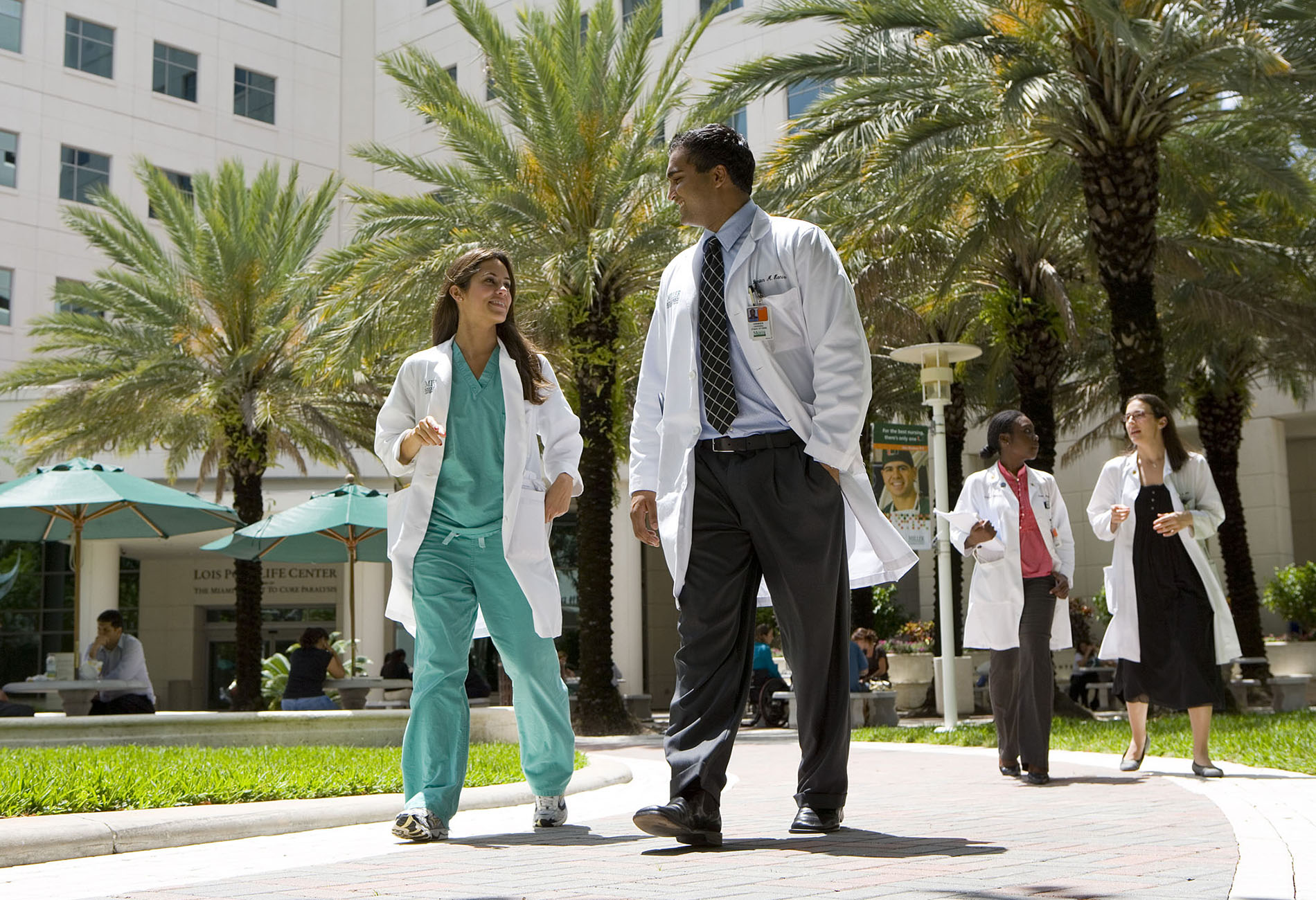 Student and a medical professional walking on the University of Miami campus.