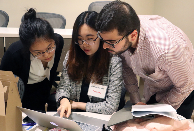 Three students collaborating on a project inside a classroom.