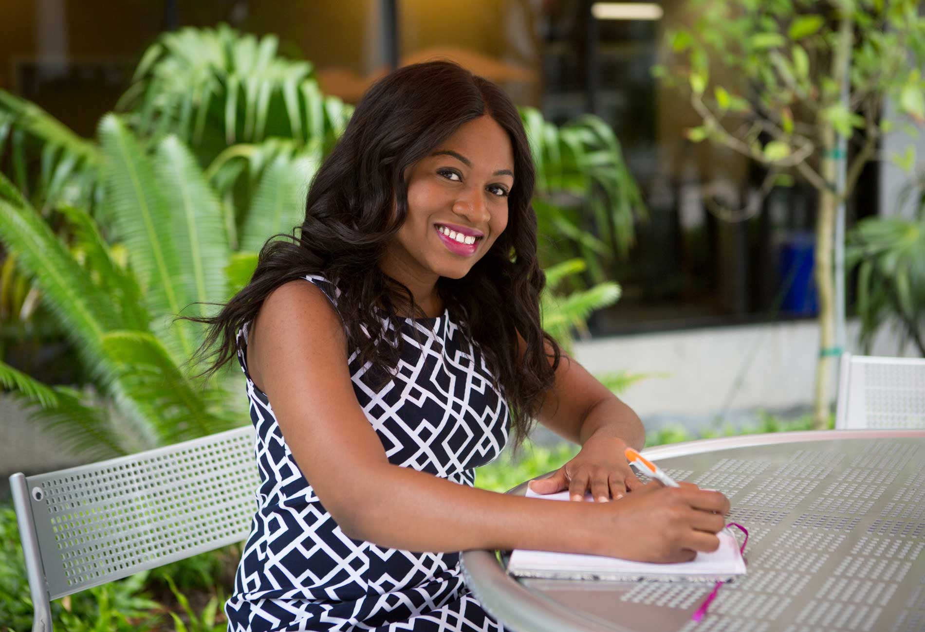 A female student studies at a table outside.