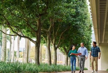 Students and professor on campus. Student and professor conversation on campus. Students walking with professor.