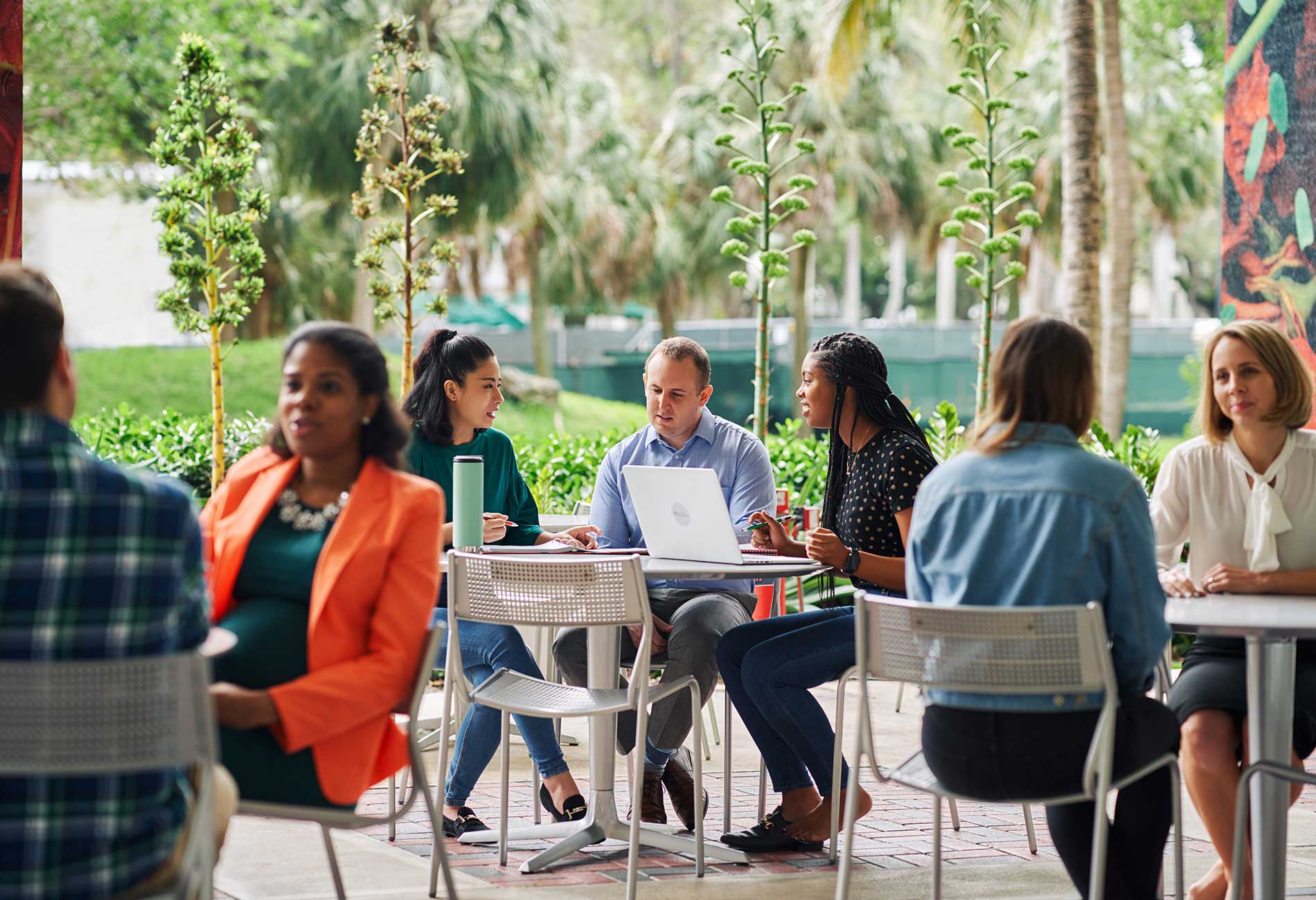 Students sit at a cafe working together with laptops