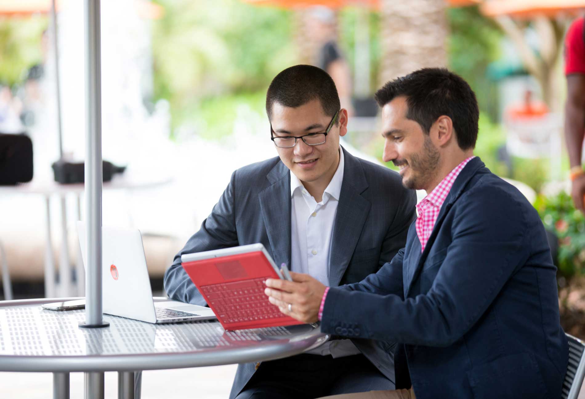 Two students sitting at a table looking at their laptops.