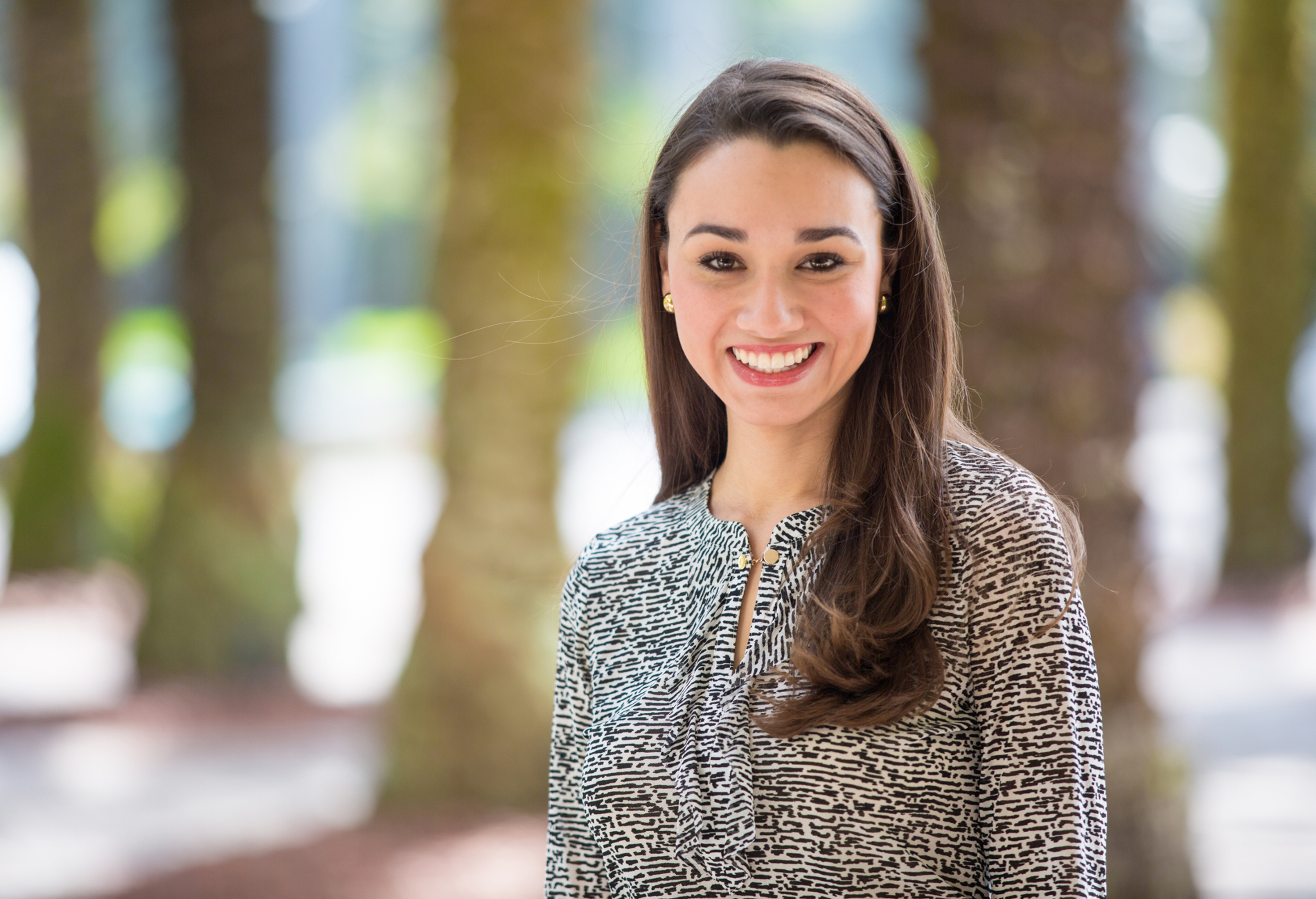 Graduate student standing outdoors by palm trees.