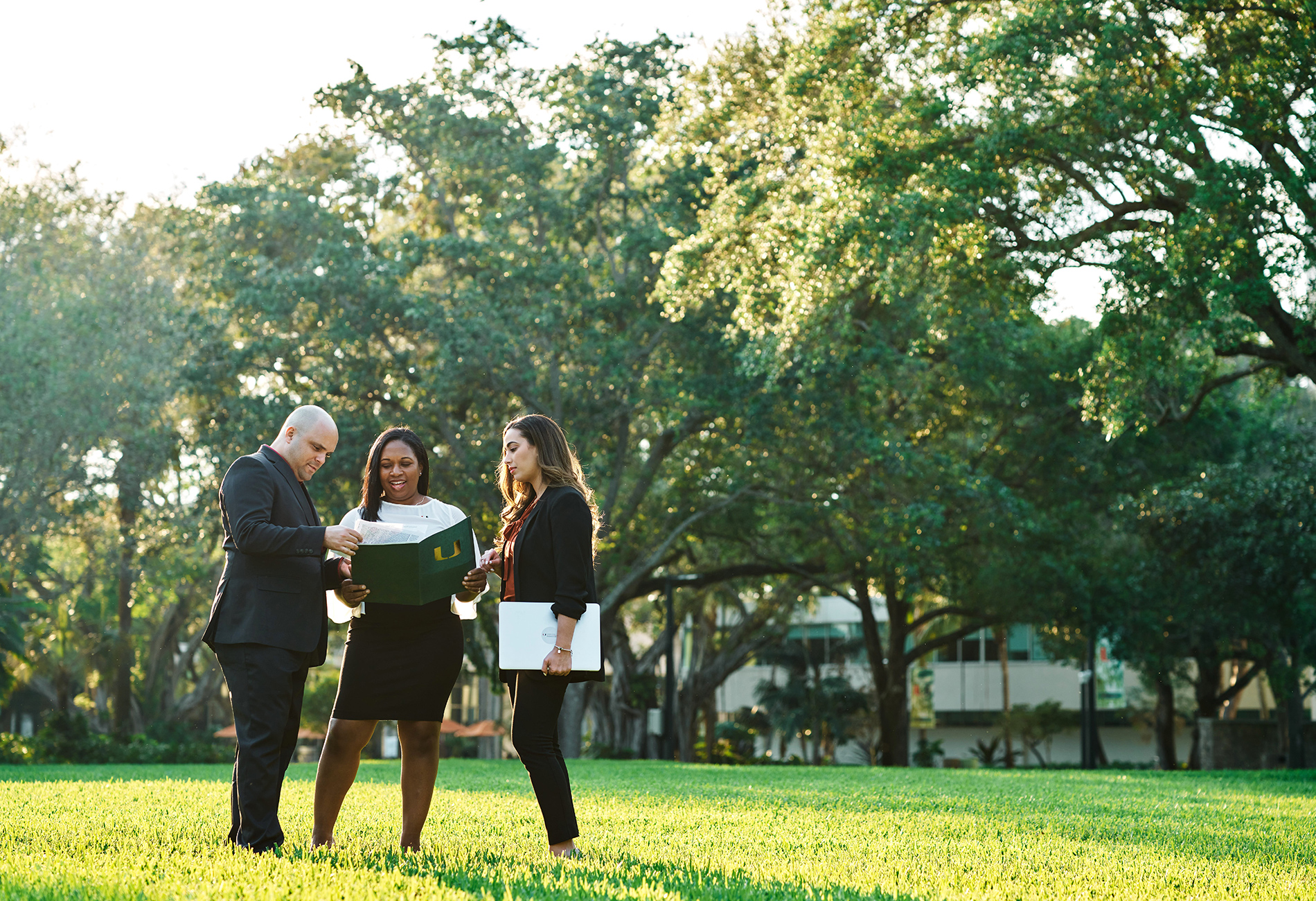 Three professional students meet outdoors on campus