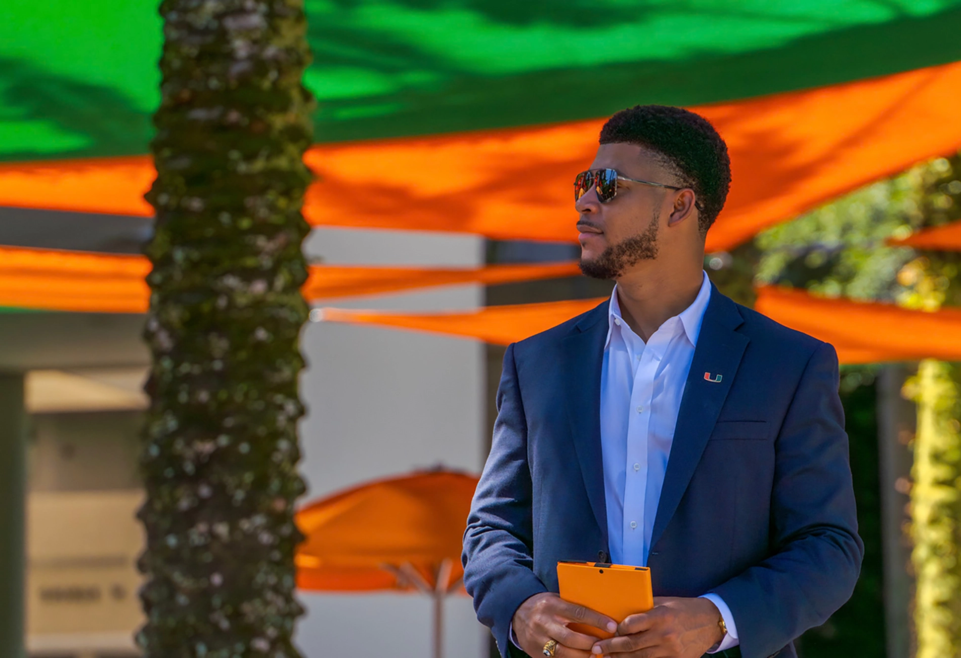 Student in a blue suit in front of the Miami Herbert Business School