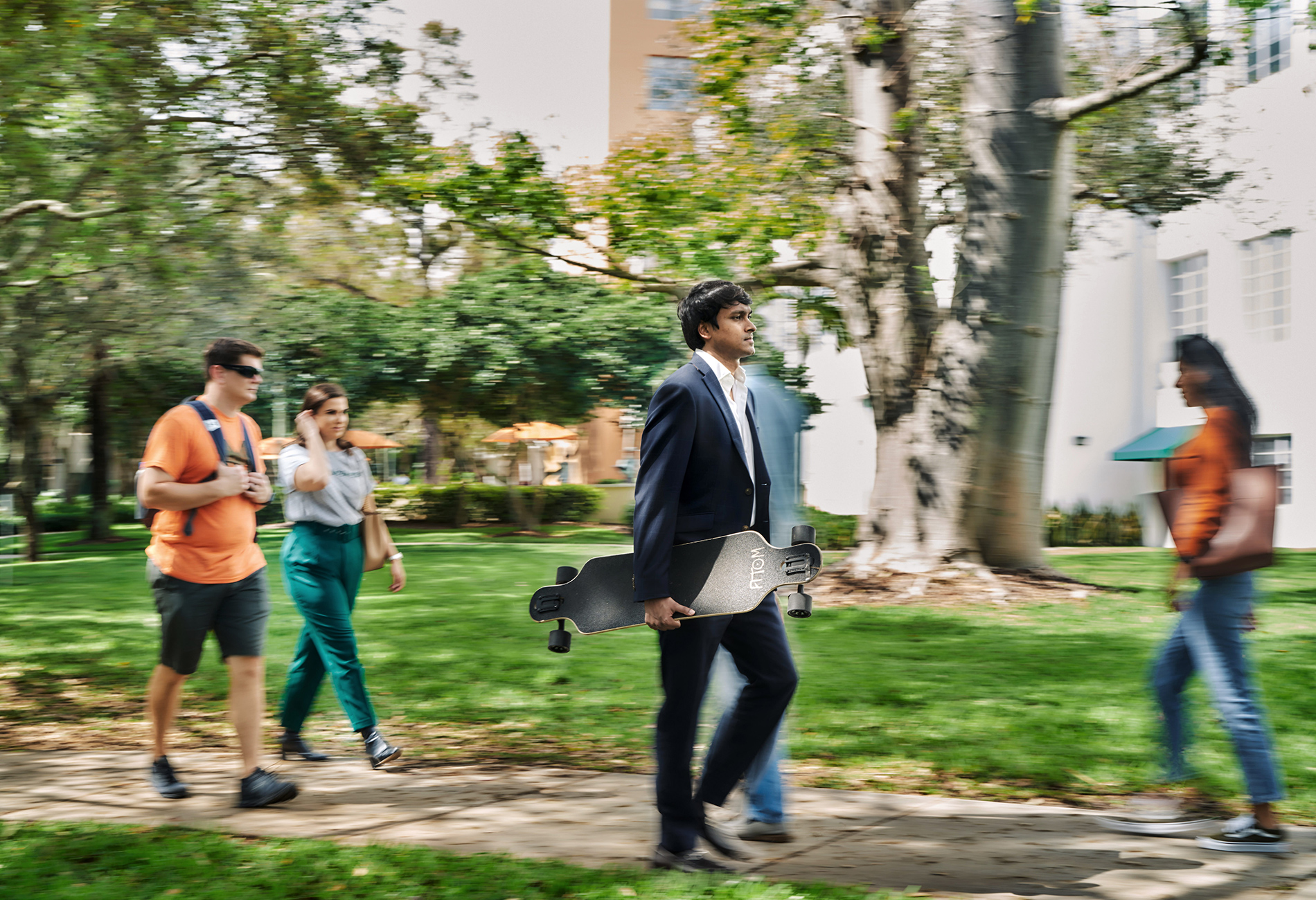 Working professional with skateboard. Professional student on campus with skateboard.
