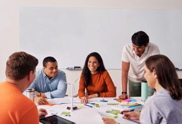 A group of students meet around a table in a classroom.