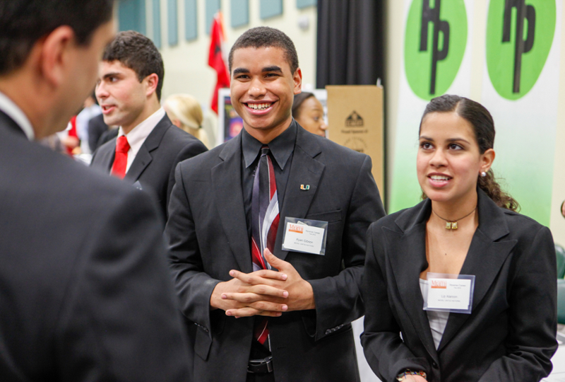 Male and female students meeting employers at career fair.