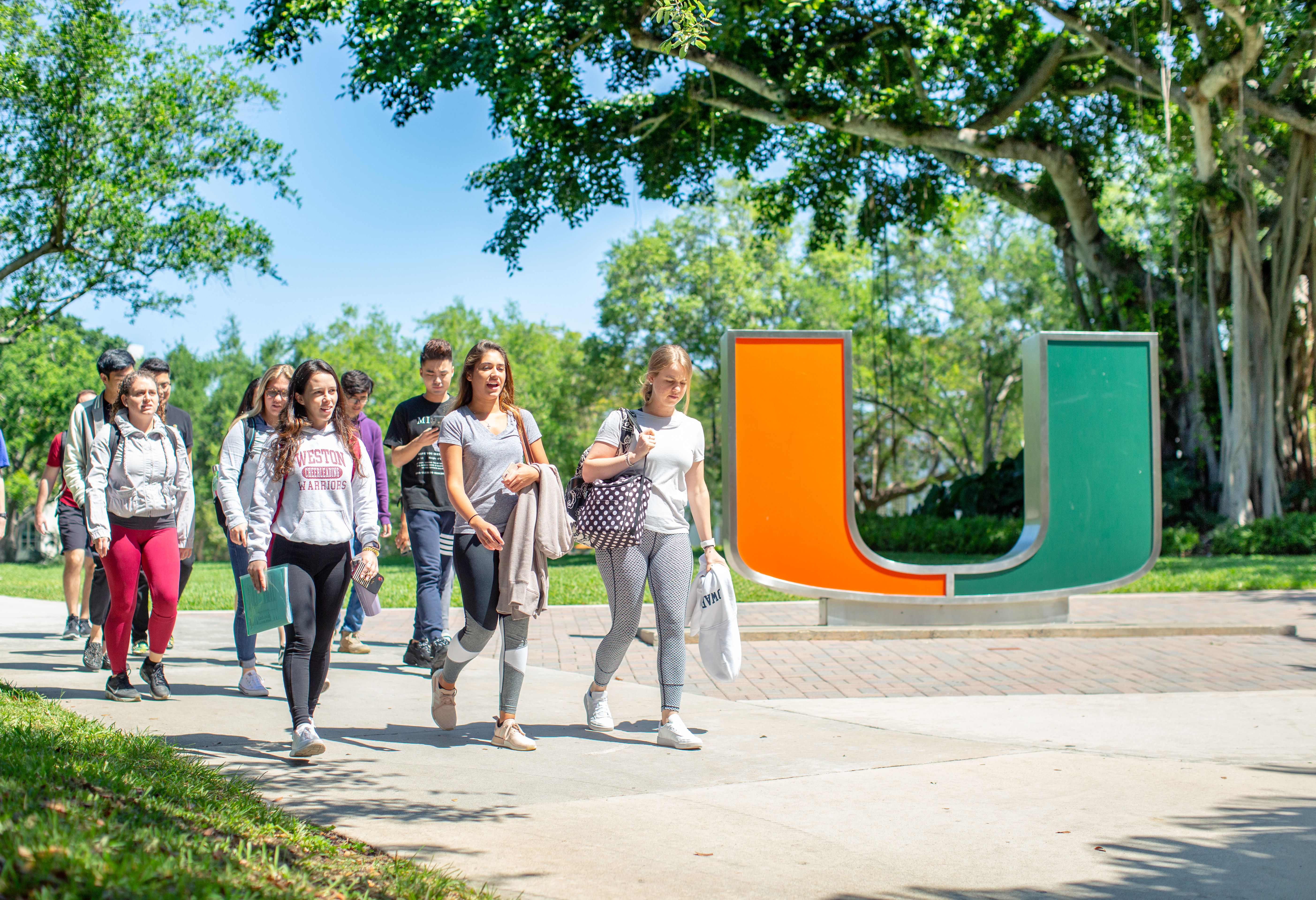 Students on campus walking in front of the orange and green U statue.