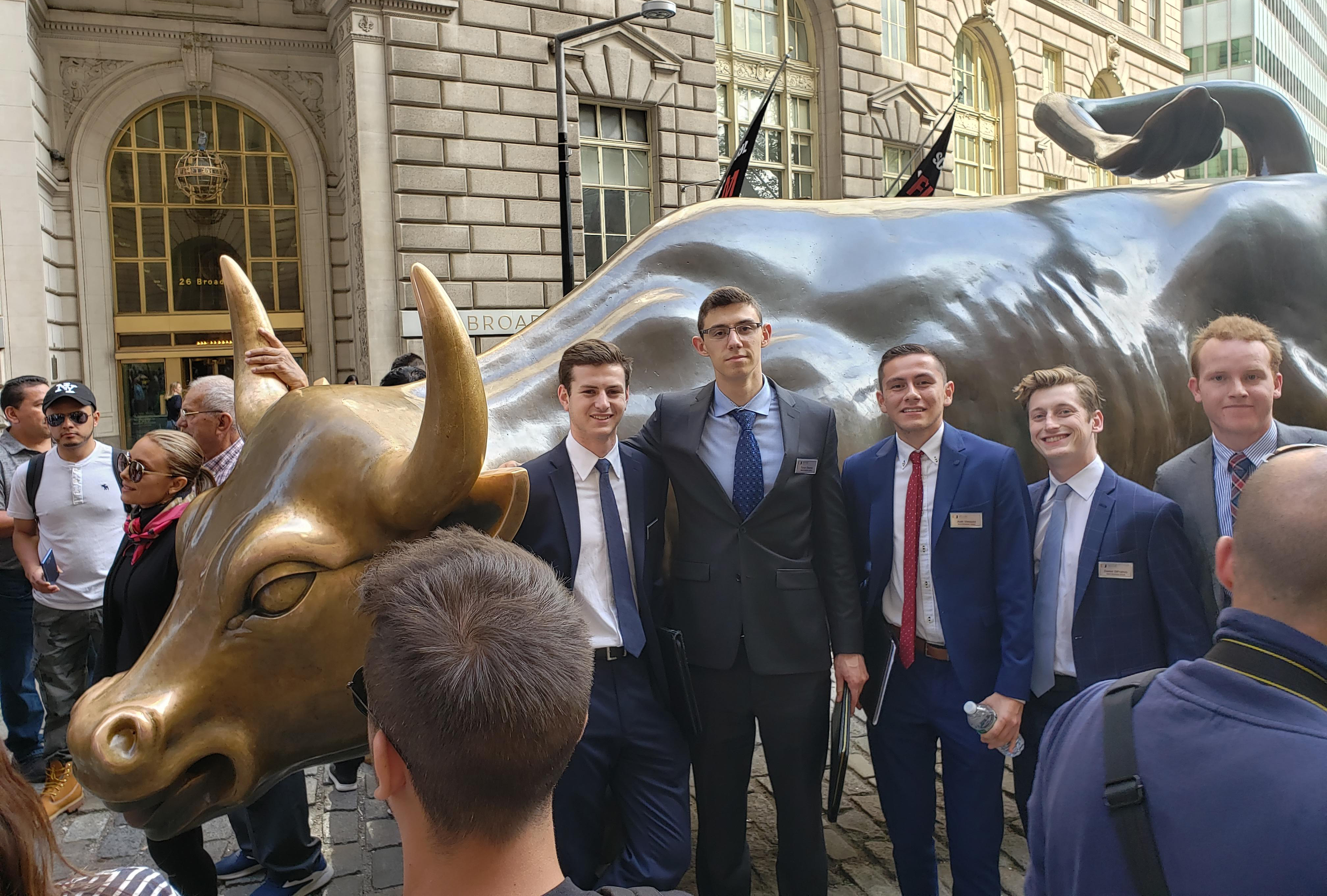 Students in formal attire pose on Wall Street.