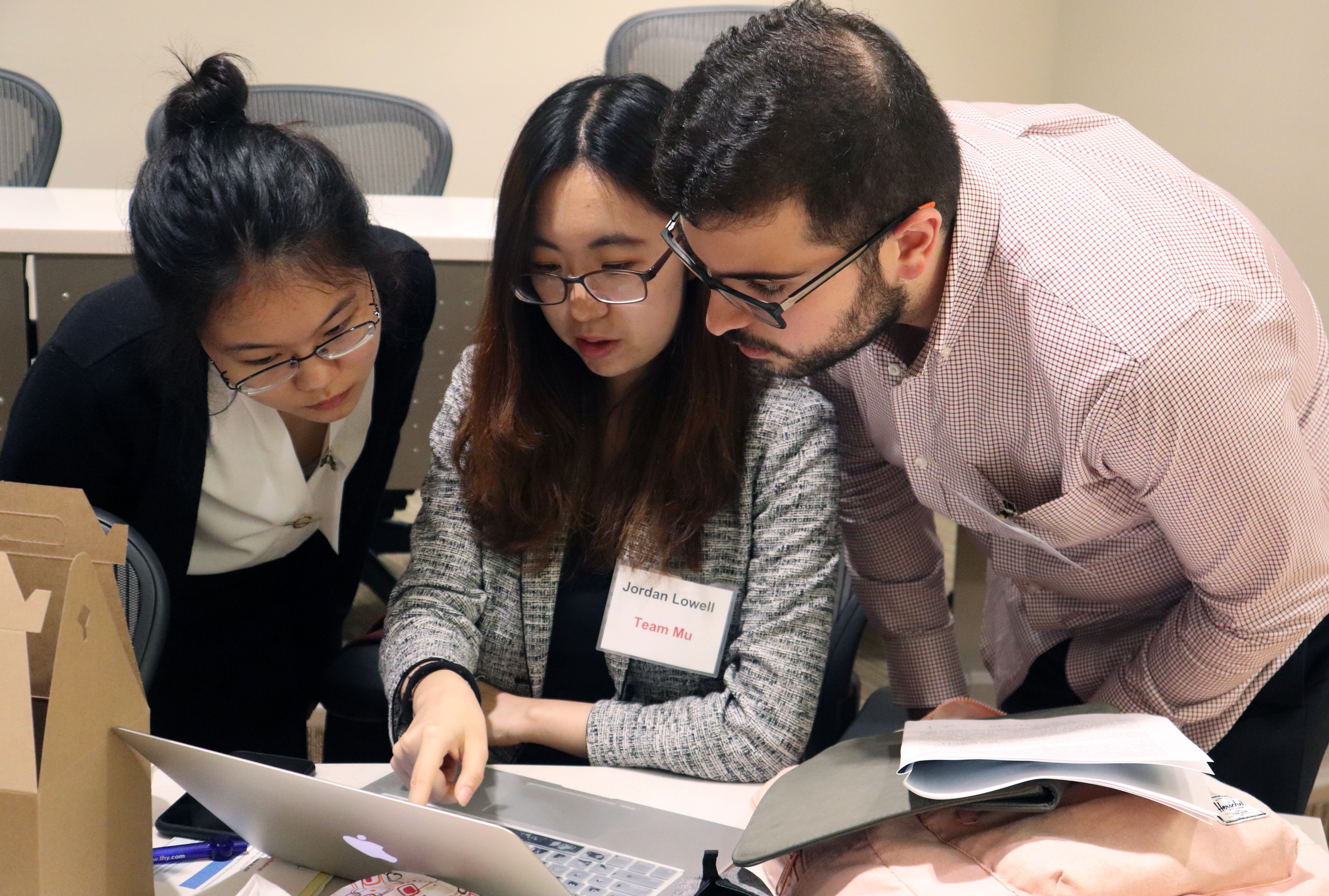 Three students gathered around a laptop.