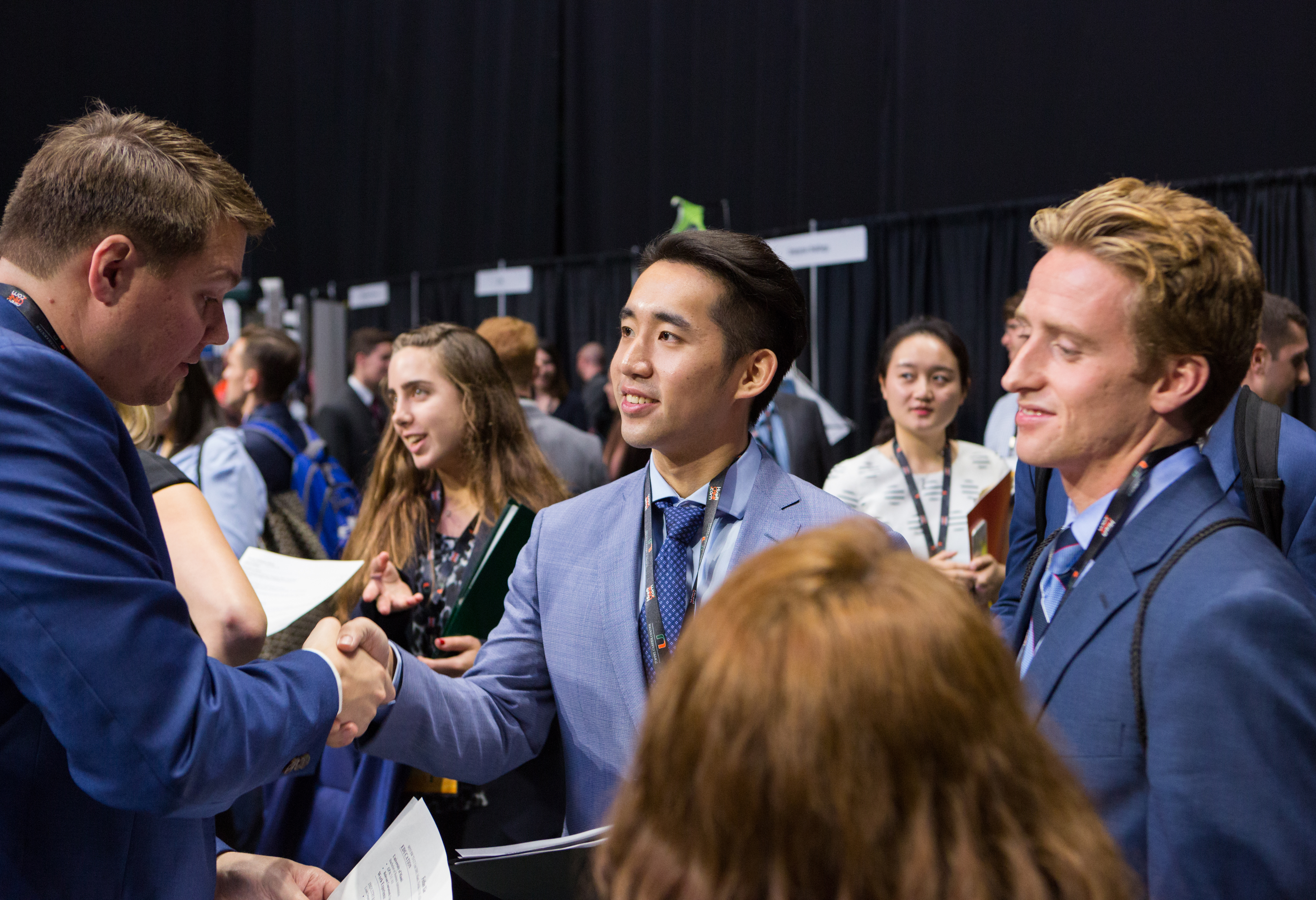 Students at a career expo shaking hands with a potential employer.