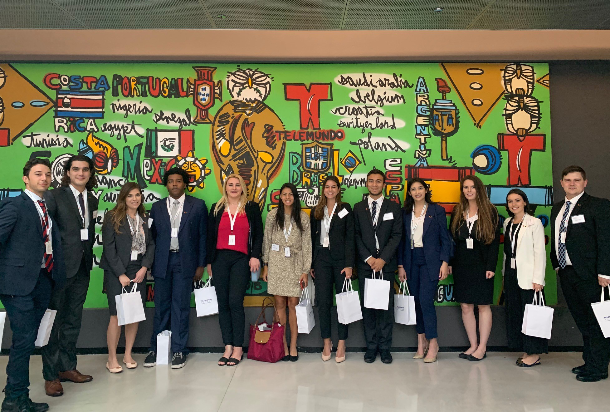 Students pose in front of a mural.