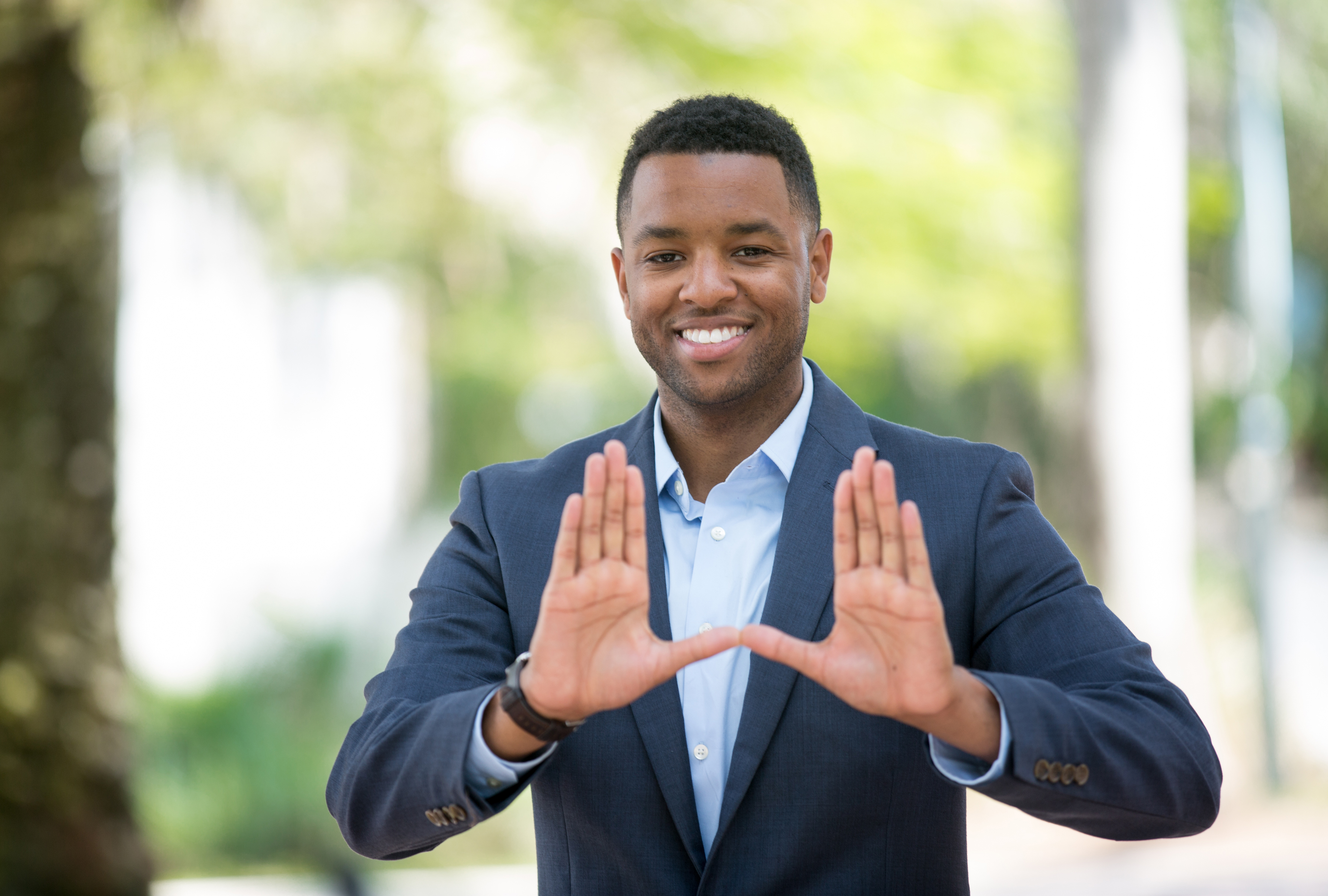 A student smiles and holds his hands in a "U" shape.