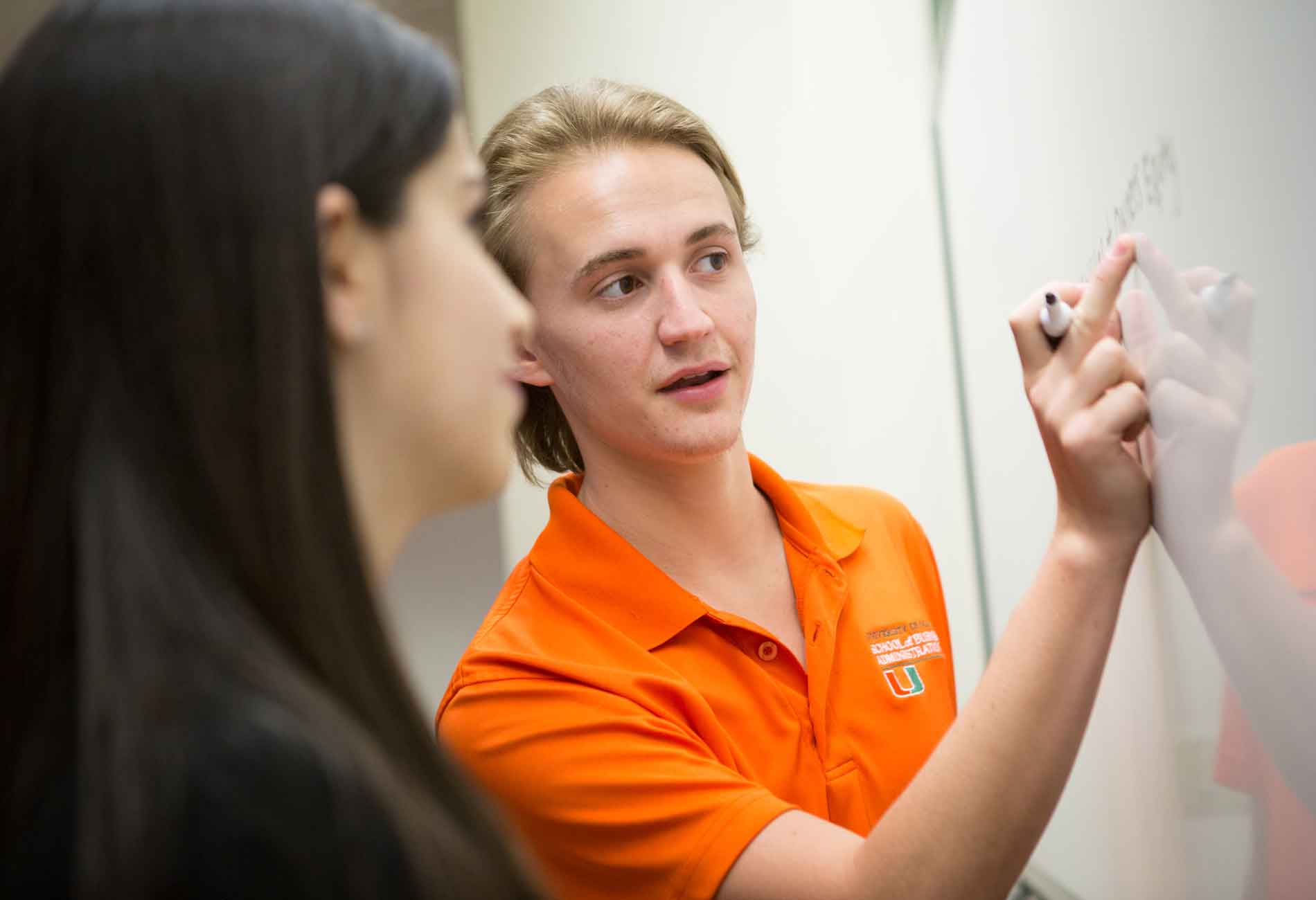 Student holds dry-erase marker demonstrating work on a whiteboard.