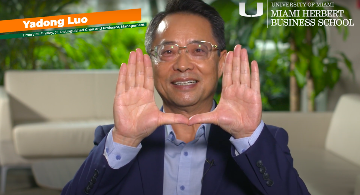 Yadong Luo sits and holds his hands up in a "U" shape.