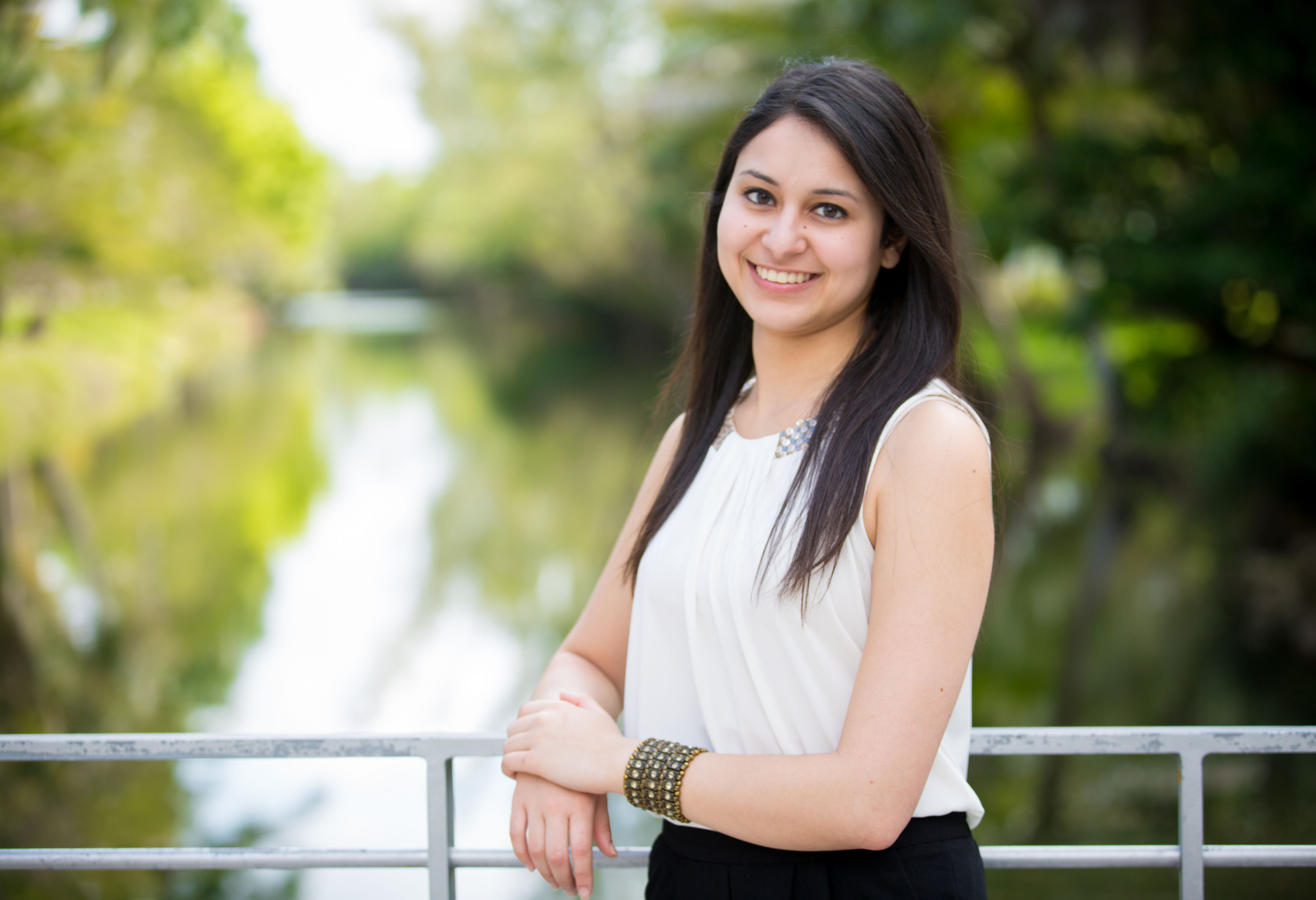 Student standing on a bridge with water in the background.