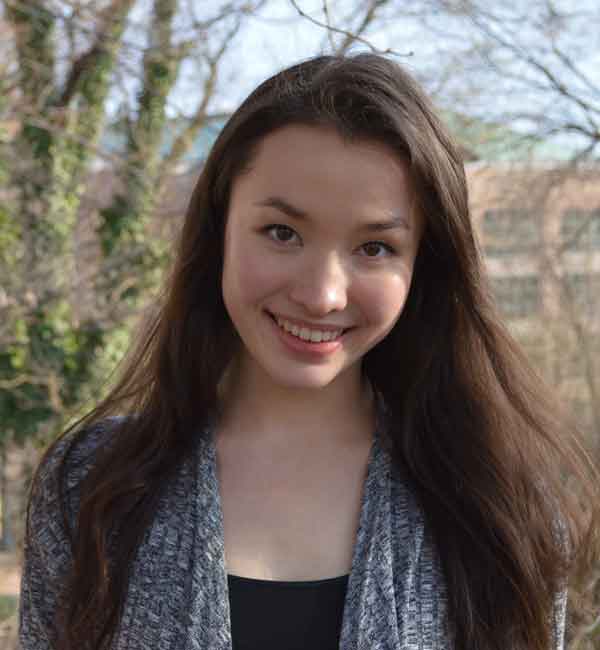 Kristiana Yao smiles warmly, trees in the background.