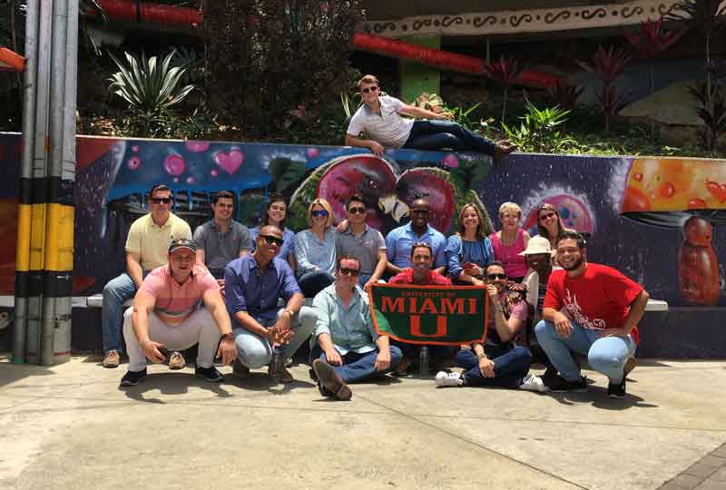 Students pose in front of a colorful mural.